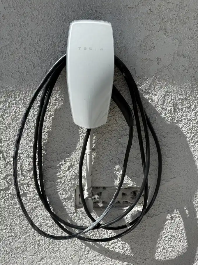 Tesla Wall Connector EV charger installed on an exterior stucco wall