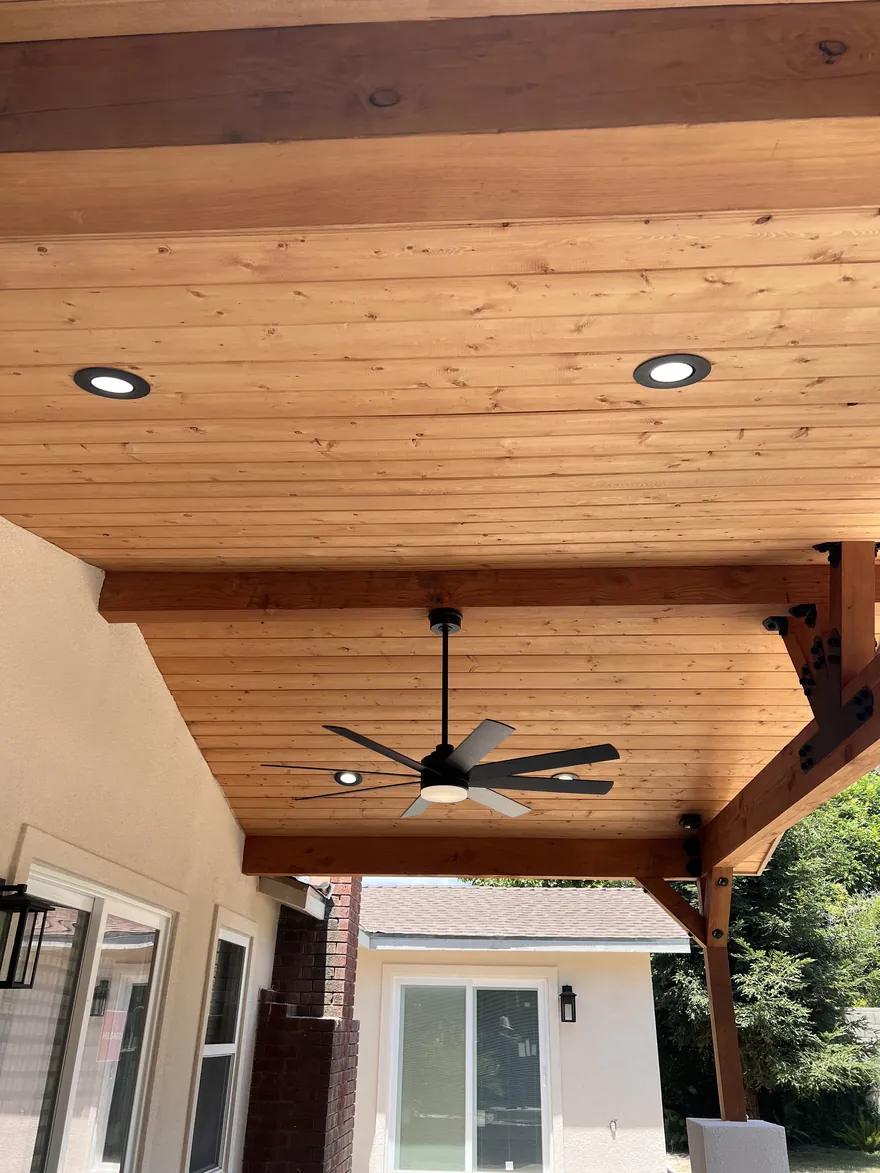 Wood plank patio ceiling with a ceiling fan and recessed lights
