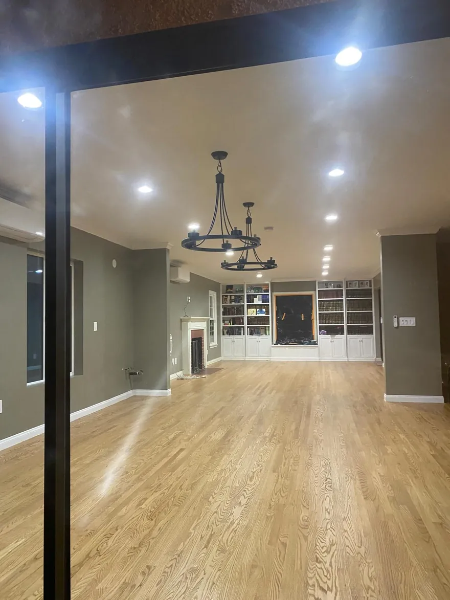 Remodeled living room with recessed lighting and two iron chandeliers