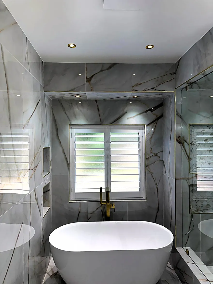Marble bathroom with recessed lighting over a freestanding tub