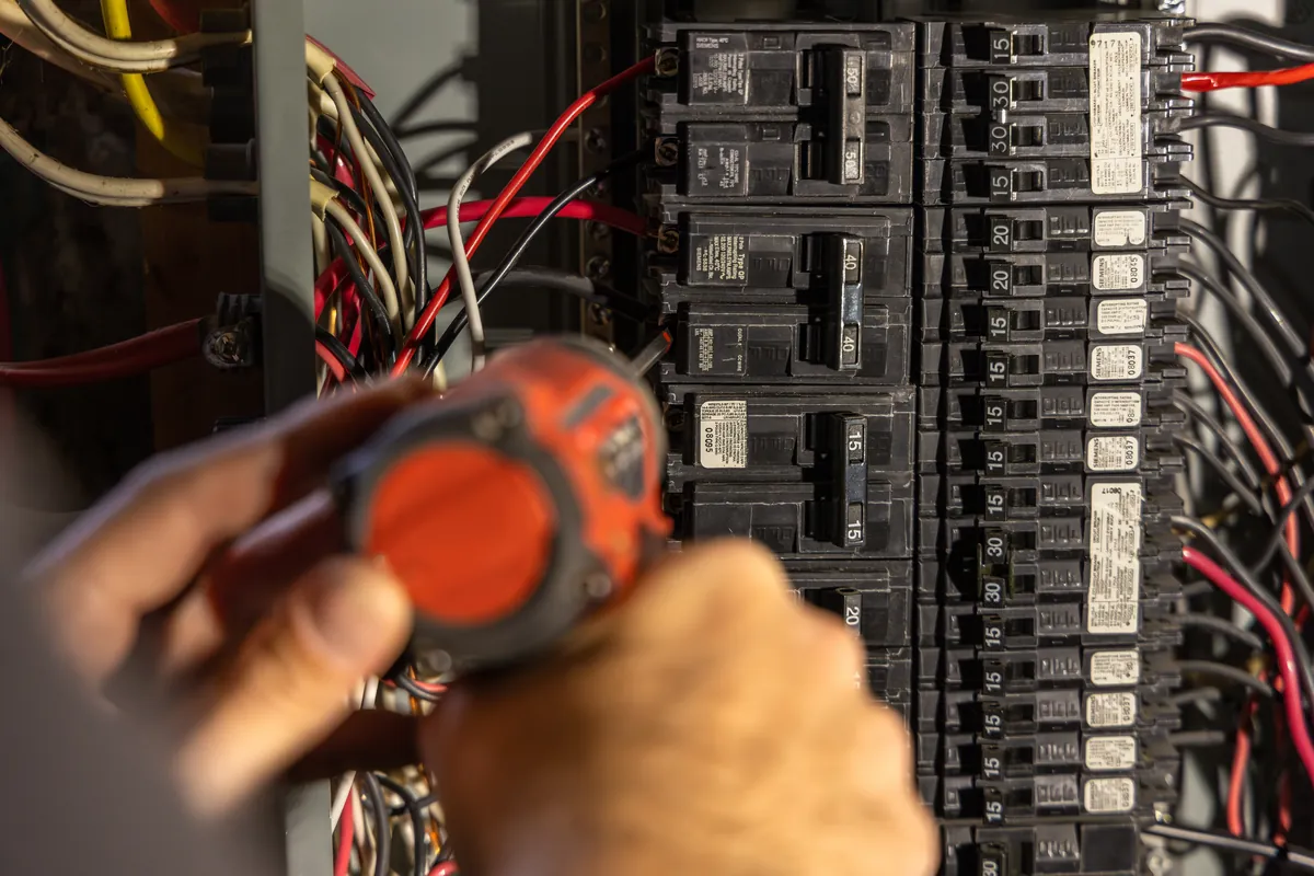 Electrician's hands installing a breaker in a loaded electrical panel